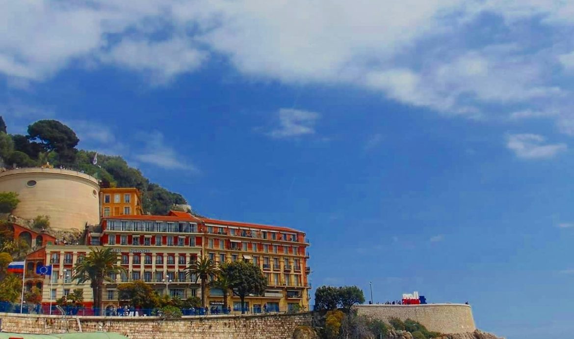 brown concrete building near green trees under blue sky during daytime